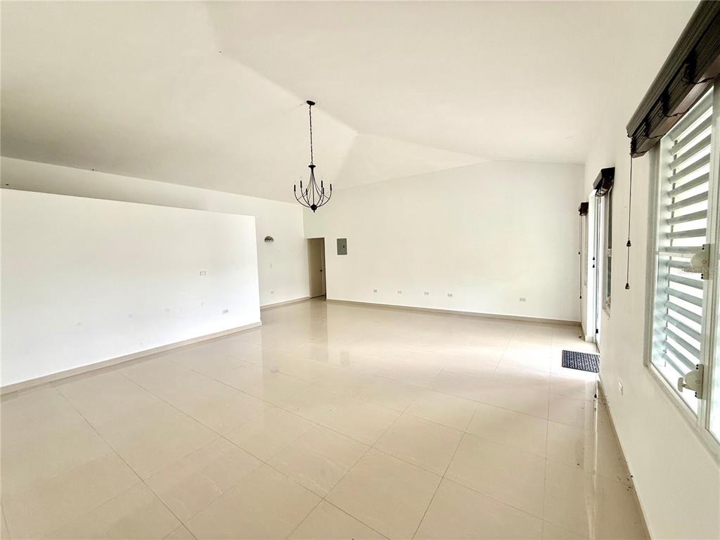 An empty room with white walls, vaulted ceilings, a chandelier, and light-colored tile flooring — 19 C1 UNIT 19, RIO GRANDE, PR