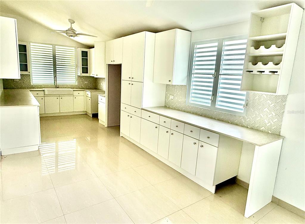 A bright kitchen features white cabinetry, light-colored tile flooring, and a patterned tile backsplash — 19 C1 UNIT 19, RIO GRANDE, PR