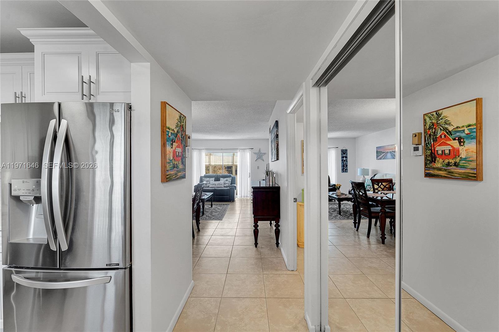 A hallway with tile flooring leads toward a living area, flanked by a stainless refrigerator — 650 NW 80th Ter # 206, Margate FL 33063, MARGATE, FL
