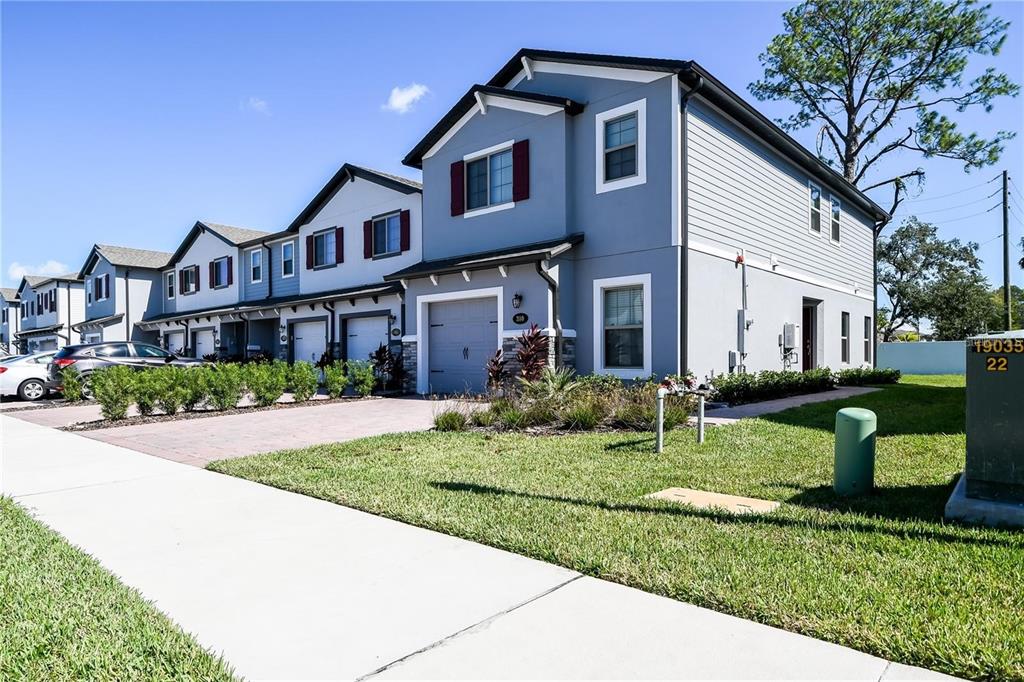 A row of two-story townhomes with blue siding and attached garages under a clear sky — 310 CEDAR BARK LANE, SANFORD, FL