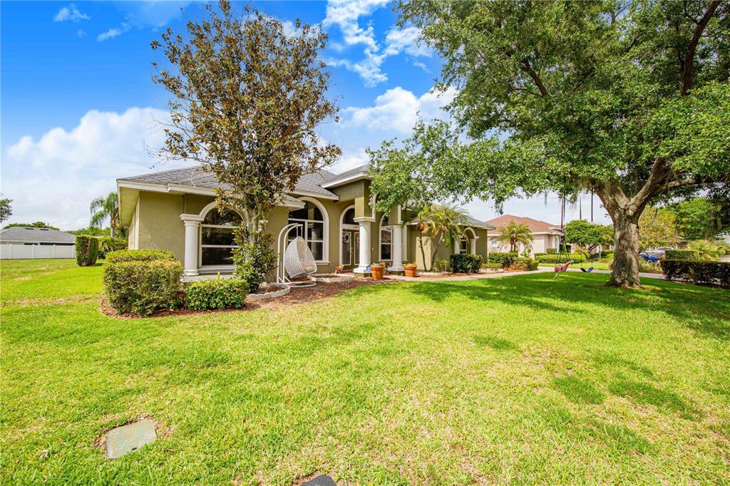 A single-story house with a green exterior, arched windows, and a large front lawn — 445 TALAMONE DRIVE, WINTER HAVEN, FL
