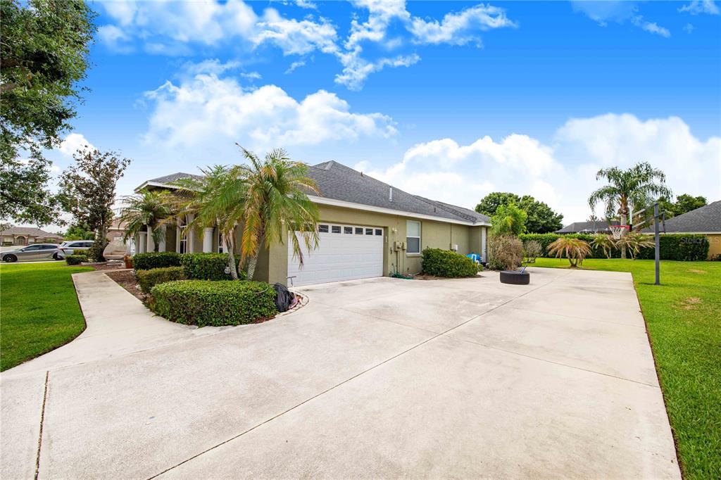 A view of a house exterior featuring a concrete driveway, garage, and landscaped front yard — 445 TALAMONE DRIVE, WINTER HAVEN, FL