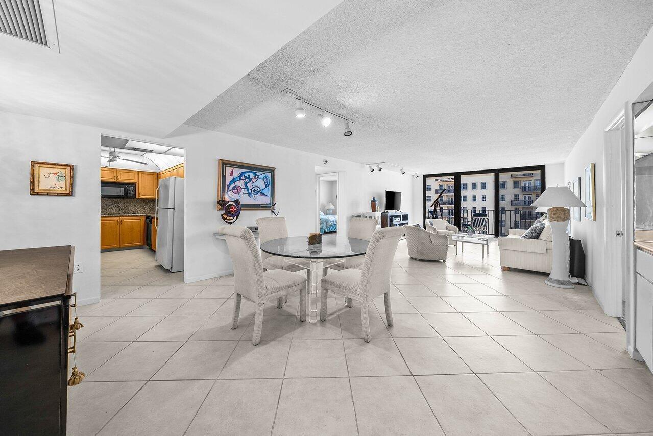 An open-concept living and dining area features white tile floors, neutral furniture, and a kitchen — 3460 S Ocean Boulevard # 6150, Palm Beach FL 33480, PALM BEACH, FL