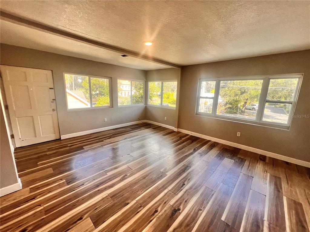 An empty room features wood-look flooring, light gray walls, and multiple windows — 1110 POINSETTIA AVENUE UNIT B, ORLANDO, FL