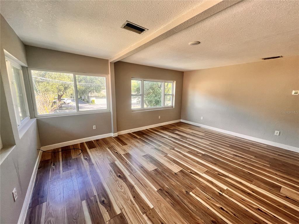 An empty room features wood-look flooring, light gray walls, and several windows — 1110 POINSETTIA AVENUE UNIT B, ORLANDO, FL