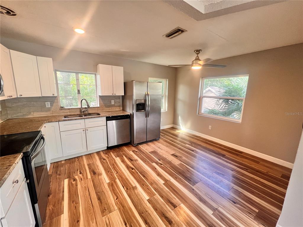 A kitchen with white cabinets, stainless steel appliances, and wood-look flooring — 1110 POINSETTIA AVENUE UNIT B, ORLANDO, FL