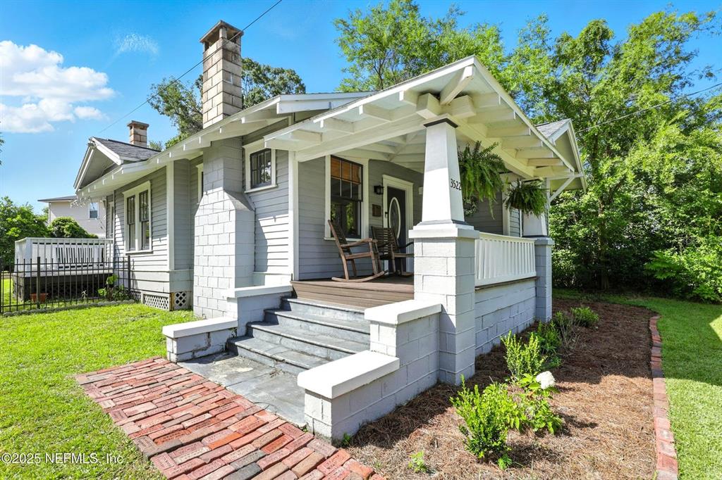 A gray bungalow features a brick walkway, a covered front porch, and a stone chimney — 3522 RANDALL STREET, JACKSONVILLE, FL