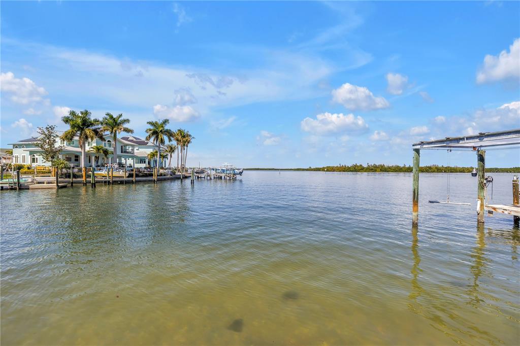 A view of a waterfront property with a dock, palm trees, and a boat lift — 2129 BAYOU GRANDE BOULEVARD NE, ST PETERSBURG, FL