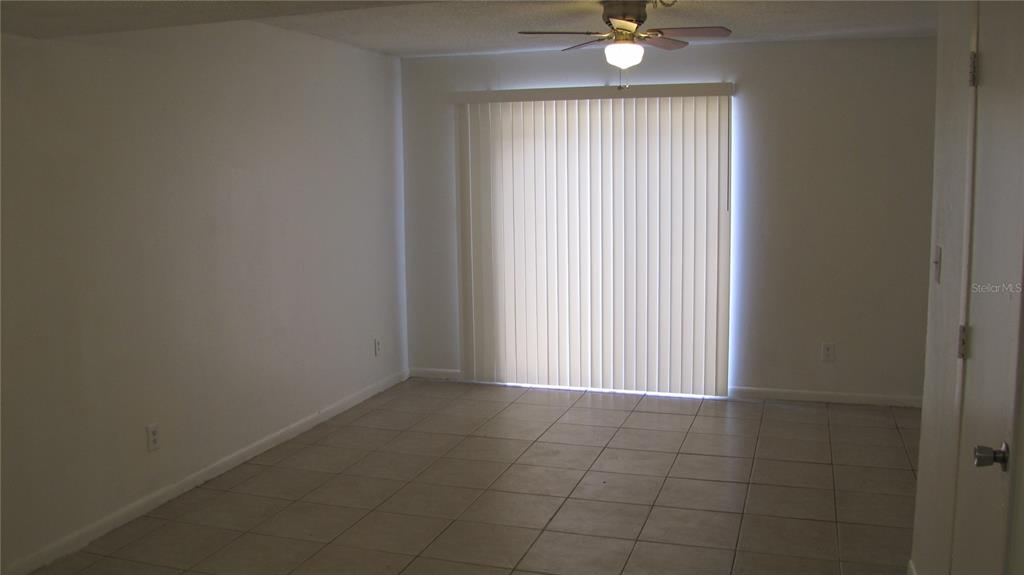 An empty room with light tile flooring, white walls, a ceiling fan, and vertical blinds — 5116 TEMPLE HEIGHTS ROAD UNIT A, TAMPA, FL