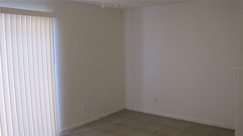 An empty room features white walls, tile flooring, and a sliding glass door with blinds — 5116 TEMPLE HEIGHTS ROAD UNIT A, TAMPA, FL