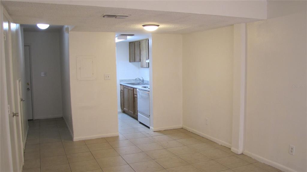 A view of a tiled living area leading into a small kitchen with wood cabinets — 5116 TEMPLE HEIGHTS ROAD UNIT A, TAMPA, FL
