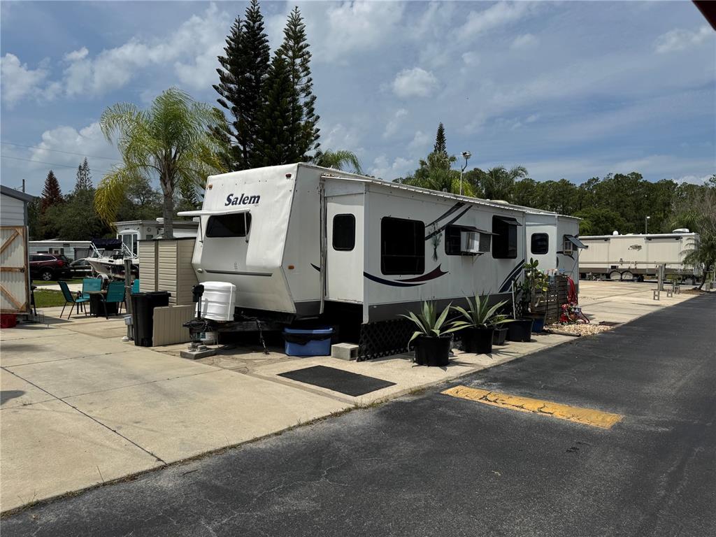 A white Salem travel trailer is parked on a concrete lot with potted plants nearby — 1310 PINE ISLAND DRIVE N, ST CLOUD, FL
