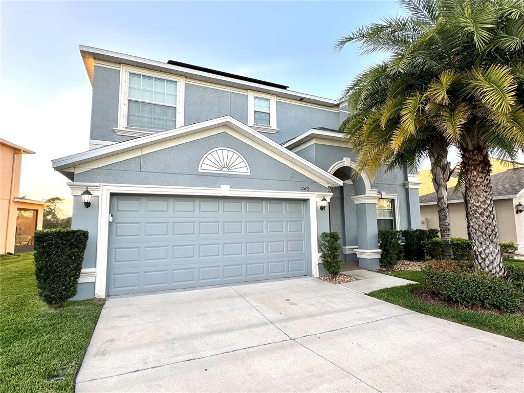 A two-story house with a gray stucco exterior, a two-car garage, and a palm tree — 11523 PERU SPRINGS PLACE, RIVERVIEW, FL