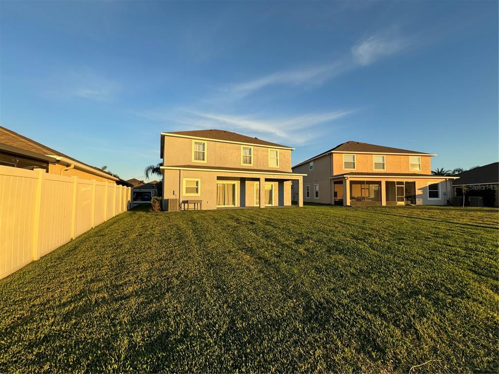 The rear exterior of two suburban houses features a large shared lawn and vinyl fencing — 11523 PERU SPRINGS PLACE, RIVERVIEW, FL