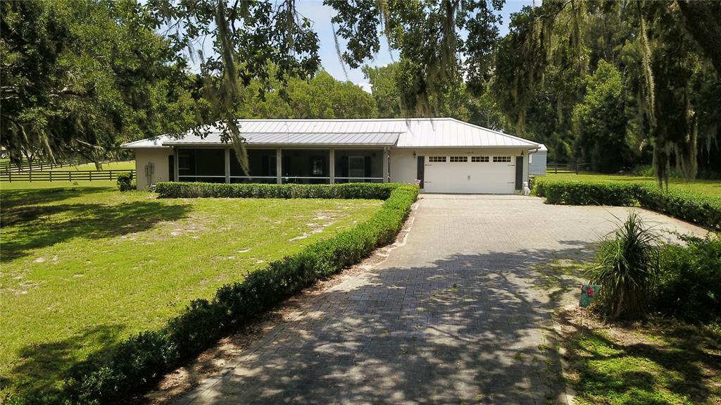 A single-story house with a metal roof, a screened porch, and a paved driveway — 16945 W PHIL C PETERS ROAD, WINTER GARDEN, FL