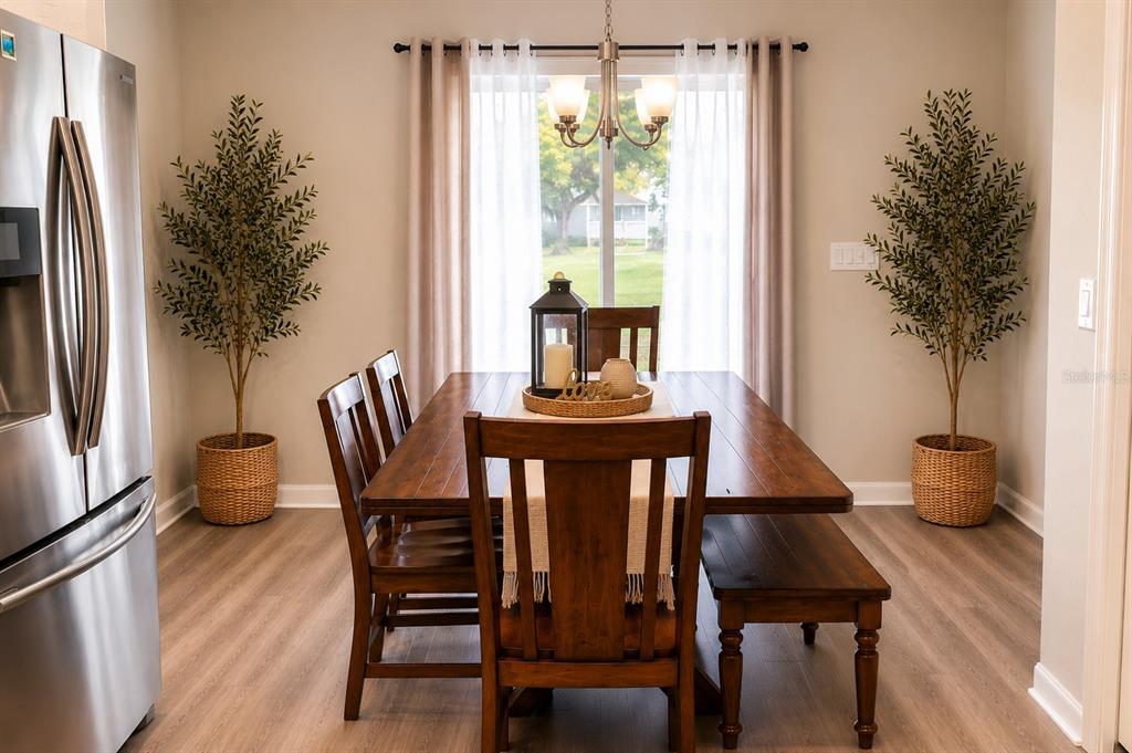 A dining room features a wooden table, chairs, a bench, and two potted olive trees — 8016 DIAMOND CREEK LANE, LAKELAND, FL