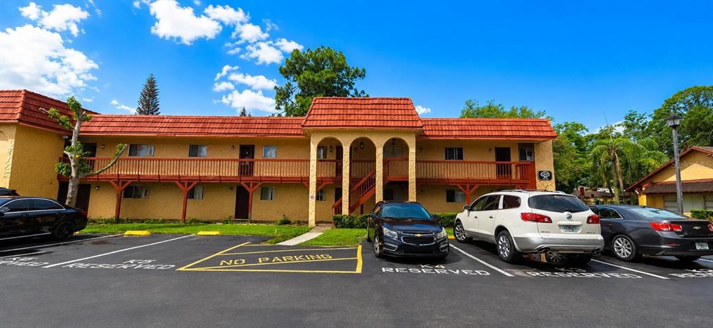 A two-story apartment building with a red tile roof and a parking lot in front — 2850 N POWERS DRIVE UNIT 83, ORLANDO, FL