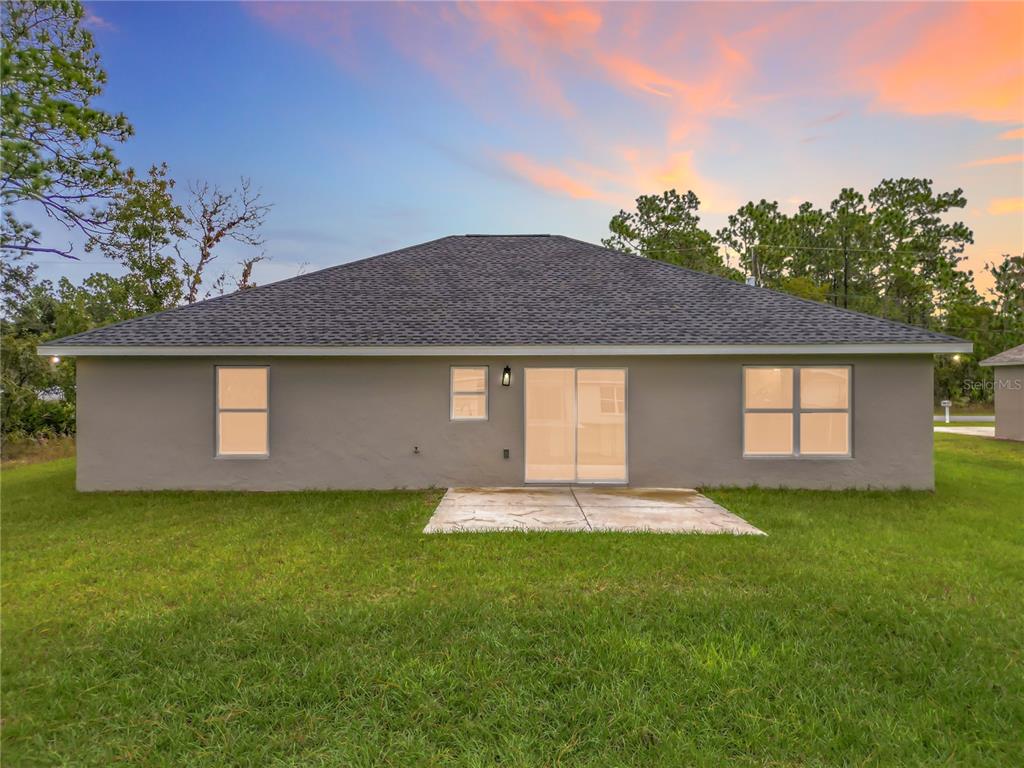 The rear exterior of a single-story house features a concrete patio and a grassy yard — 6526 N EARLSHIRE TERRACE, CITRUS SPRINGS, FL