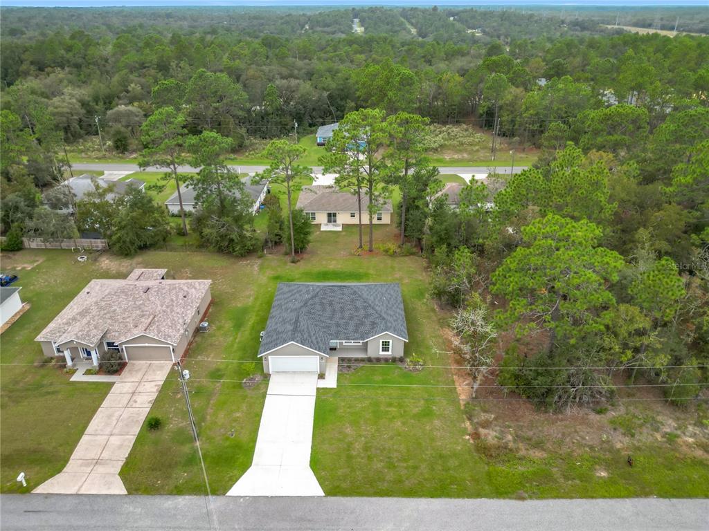 An aerial view shows a single-story house with a gray roof and a concrete driveway — 6526 N EARLSHIRE TERRACE, CITRUS SPRINGS, FL
