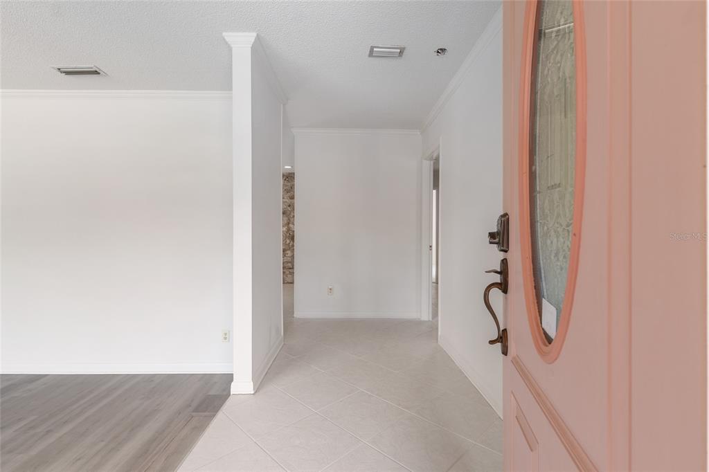 An entryway with light tile flooring leads to a hallway with white walls and trim — 1410 NW 28TH STREET, GAINESVILLE, FL