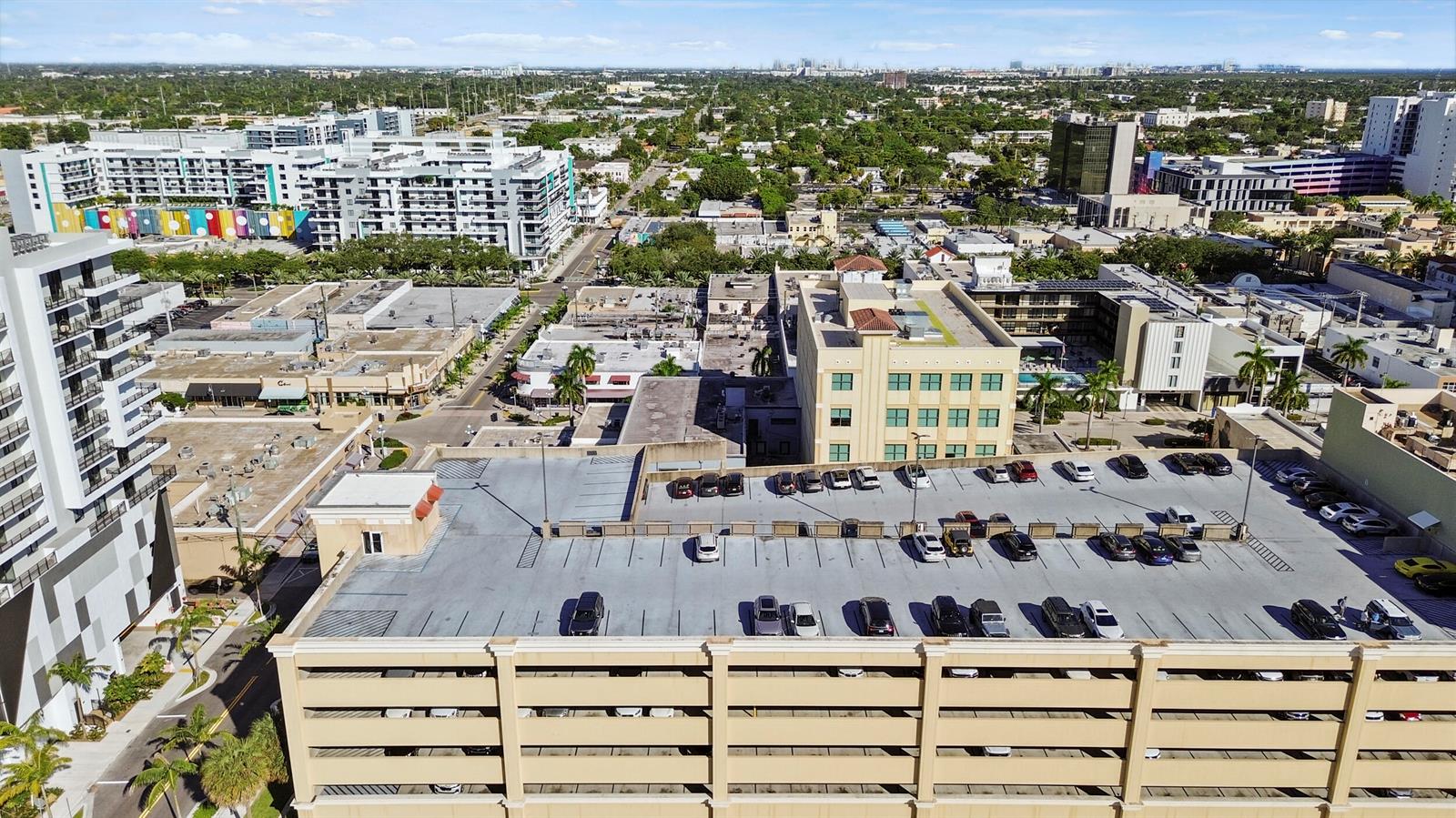 An aerial view of a parking garage rooftop with cars parked in an urban setting — 1940 Harrison Street, Hollywood FL 33020, HOLLYWOOD, FL