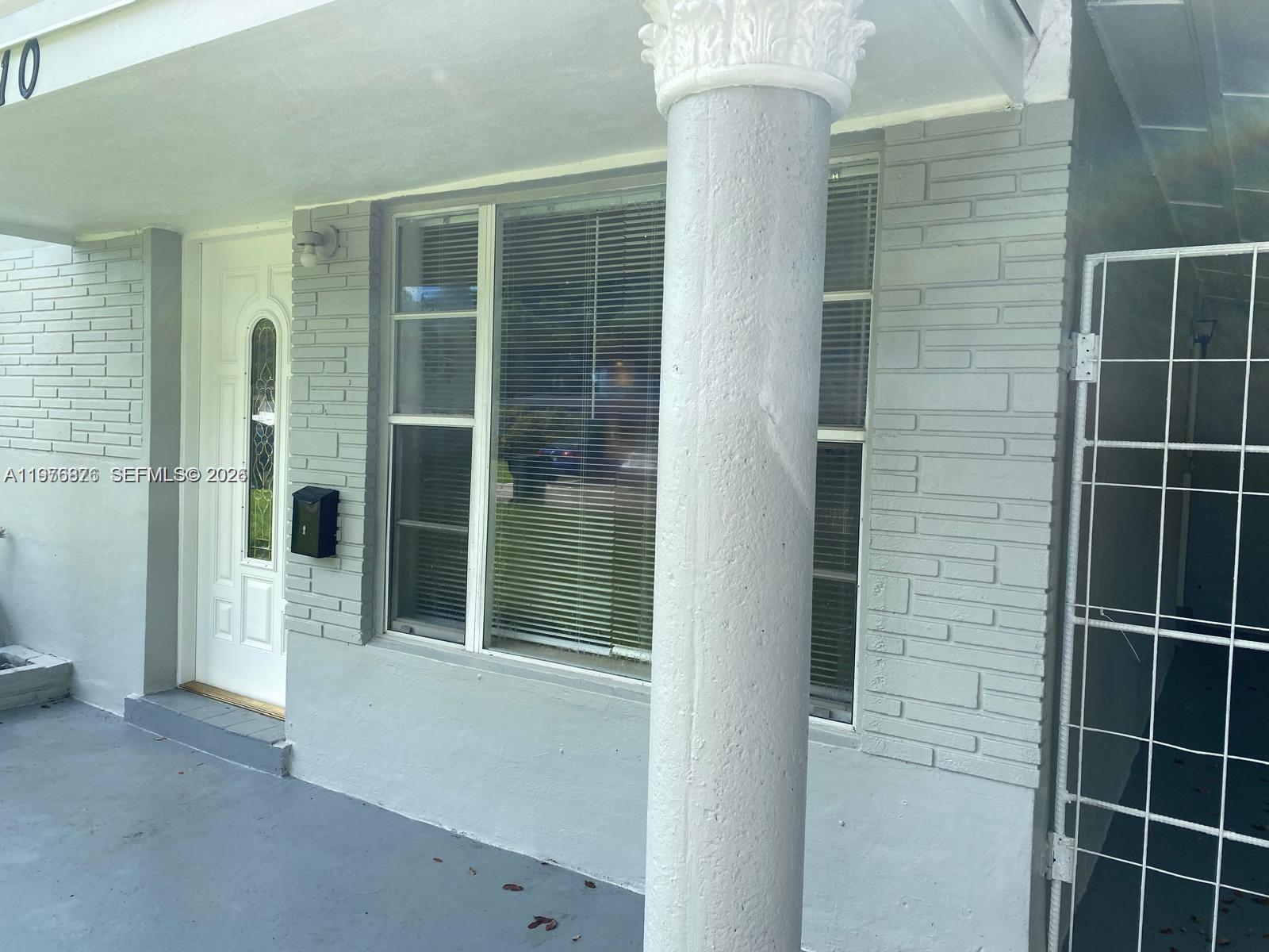 A gray painted brick exterior features a white front door and a decorative column — 5710 Douglas St, Hollywood FL 33021, HOLLYWOOD, FL