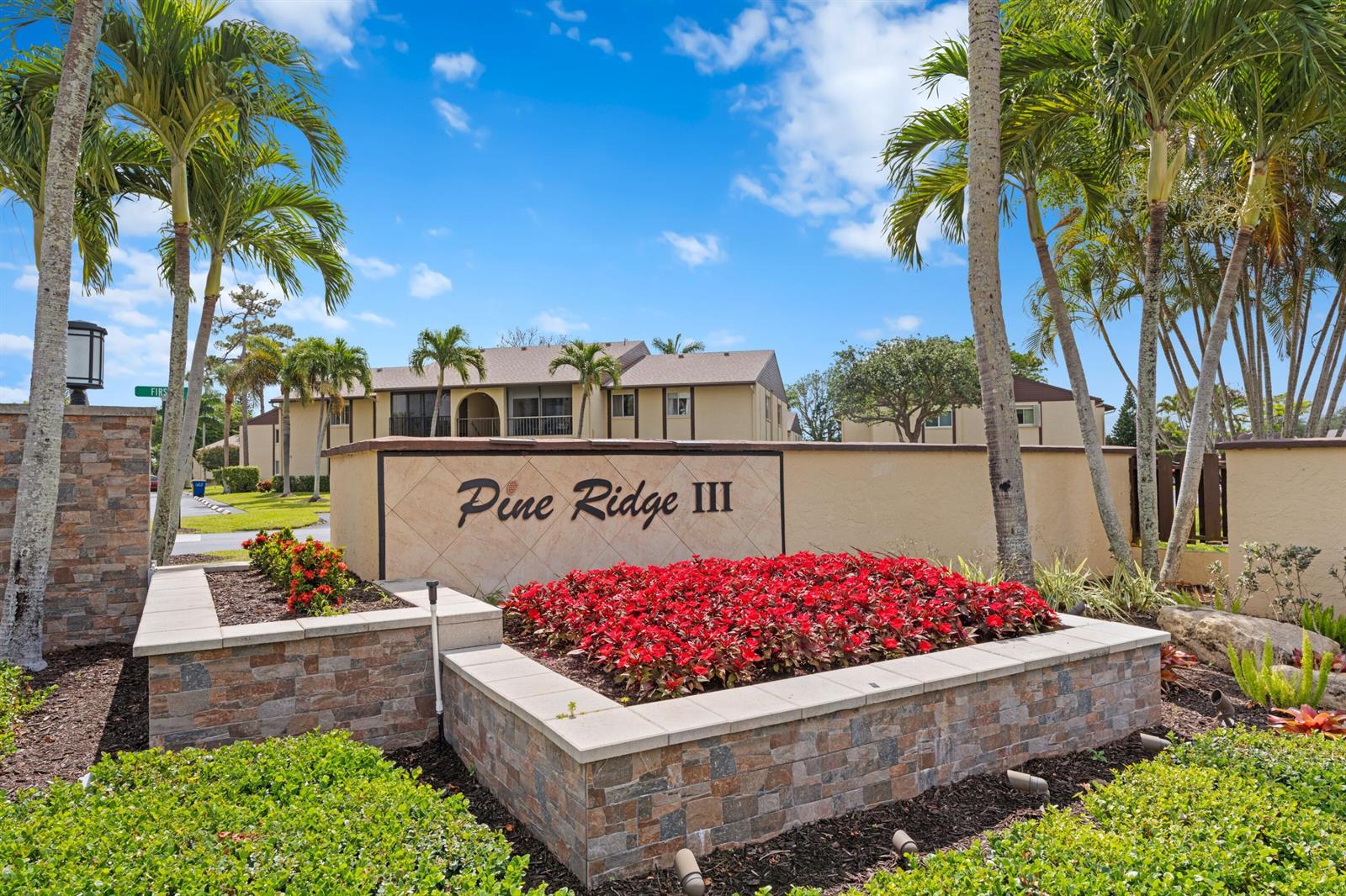A stone-walled entrance sign for Pine Ridge III features a large bed of red flowers — 339 Pine Ridge Circle # 1, FL 33463, FL