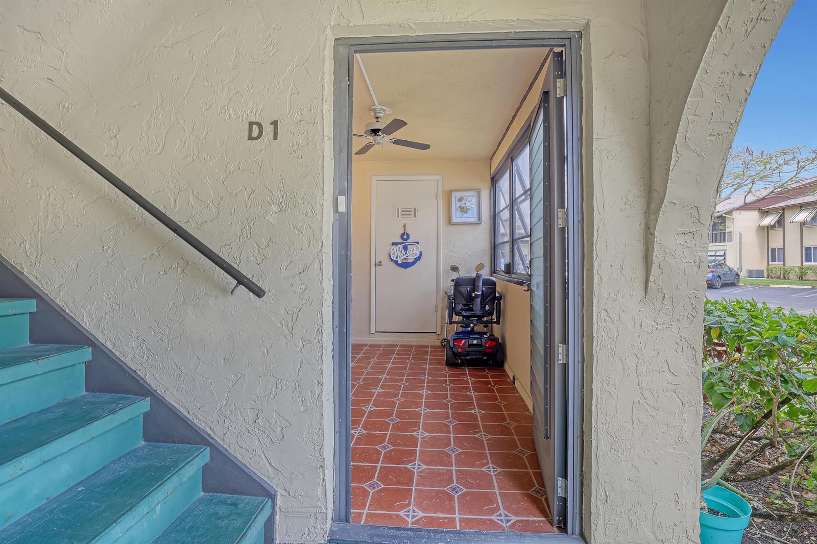 An exterior view of a ground-level apartment entrance with teal stairs and a tiled porch — 339 Pine Ridge Circle # 1, FL 33463, FL