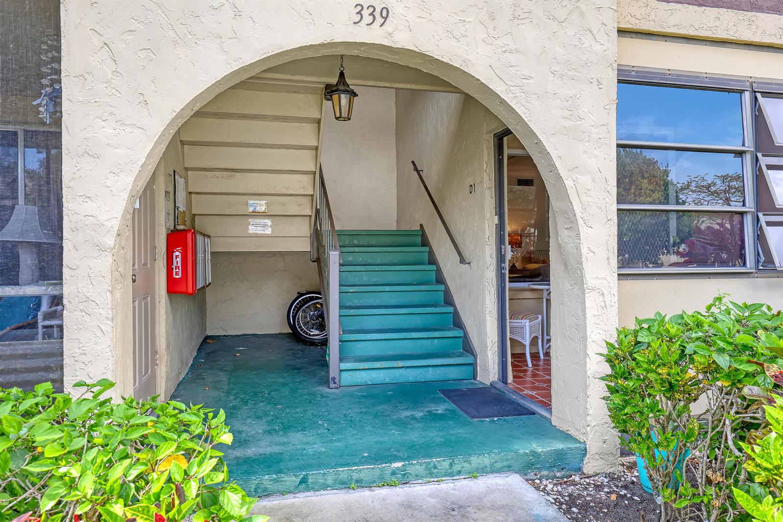 An exterior view of an apartment building entrance with green stairs and a red fire box — 339 Pine Ridge Circle # 1, FL 33463, FL