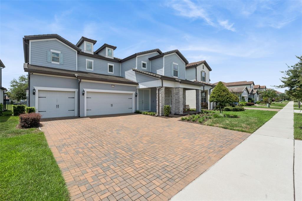 A two-story house with a blue exterior, stone accents, and a paved driveway — 9070 WOODLAND FOREST ROAD, ORLANDO, FL