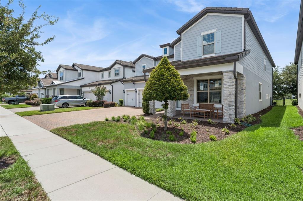 A two-story townhouse with light blue siding, stone accents, and a paved driveway — 9070 WOODLAND FOREST ROAD, ORLANDO, FL