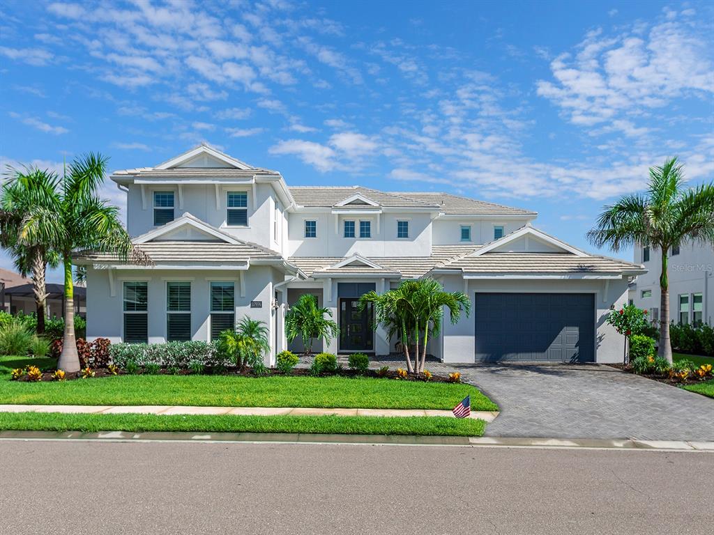 A two-story white house with a gray roof, a two-car garage, and palm trees — 17974 PALMISTE DRIVE, LAKEWOOD RANCH, FL