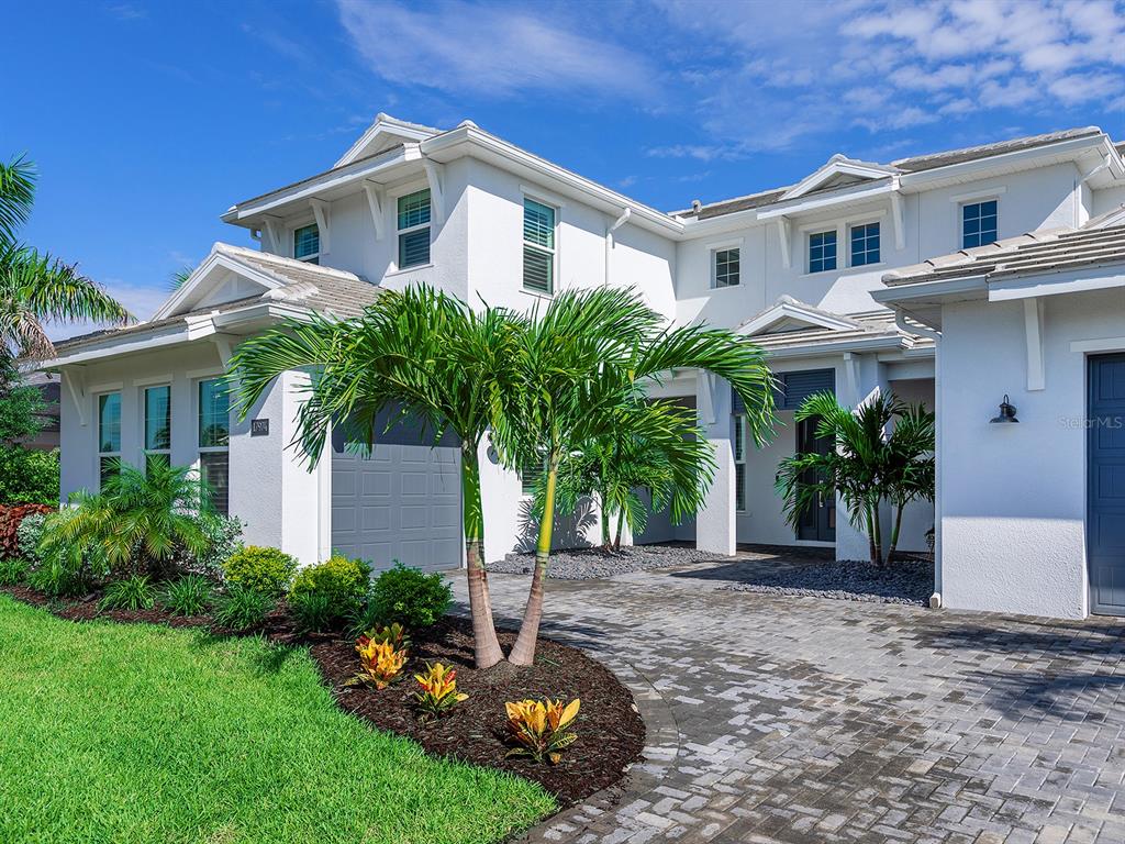 A two-story white house features a paved driveway, palm trees, and a landscaped front yard — 17974 PALMISTE DRIVE, LAKEWOOD RANCH, FL