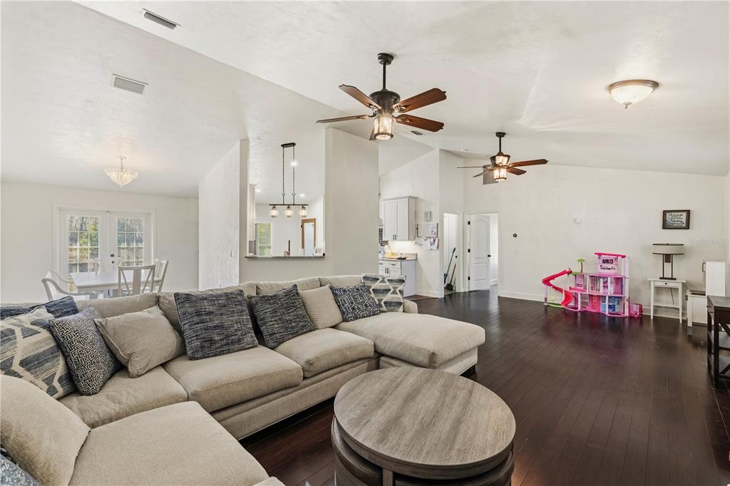 A living room with dark hardwood floors, a sectional sofa, and two ceiling fans — 3353 NE 71ST AVENUE, HIGH SPRINGS, FL