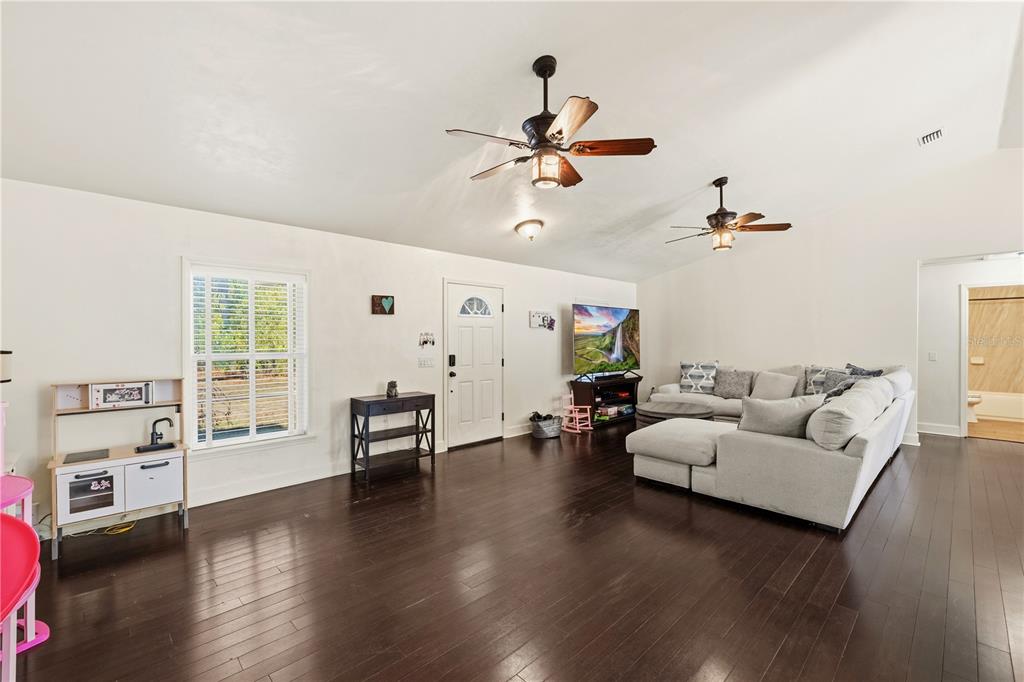 A living room with dark hardwood floors, two ceiling fans, and a sectional sofa — 3353 NE 71ST AVENUE, HIGH SPRINGS, FL