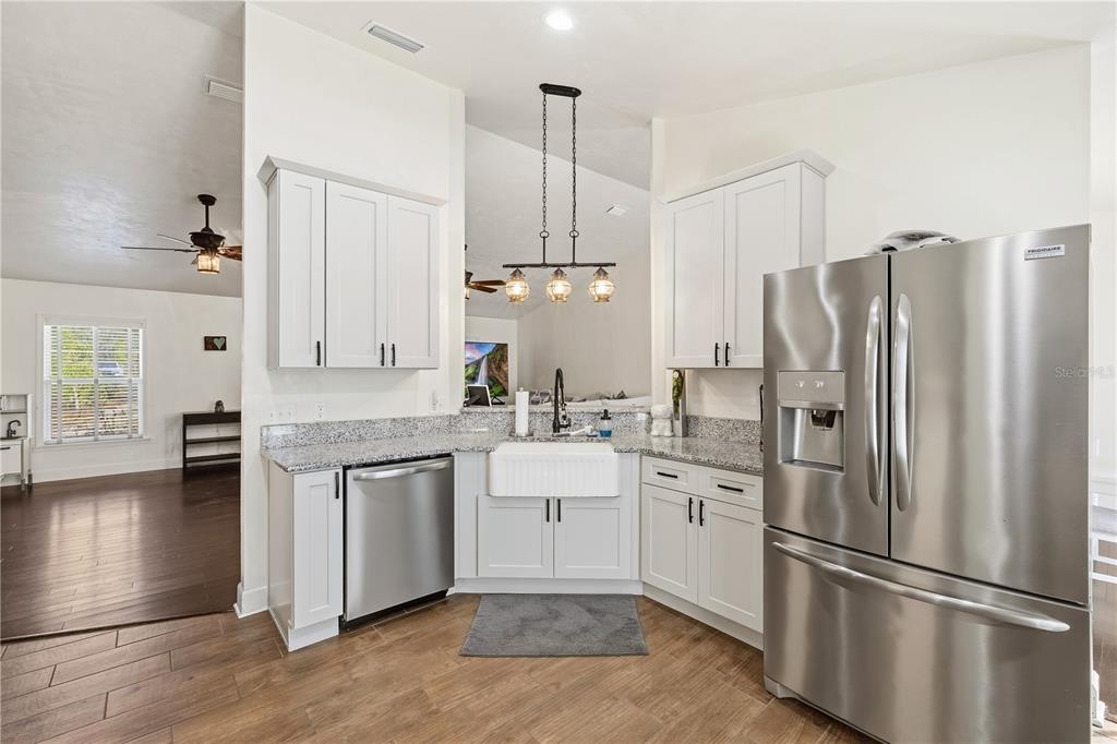 A kitchen with white cabinets, granite countertops, a farmhouse sink, and stainless steel appliances — 3353 NE 71ST AVENUE, HIGH SPRINGS, FL