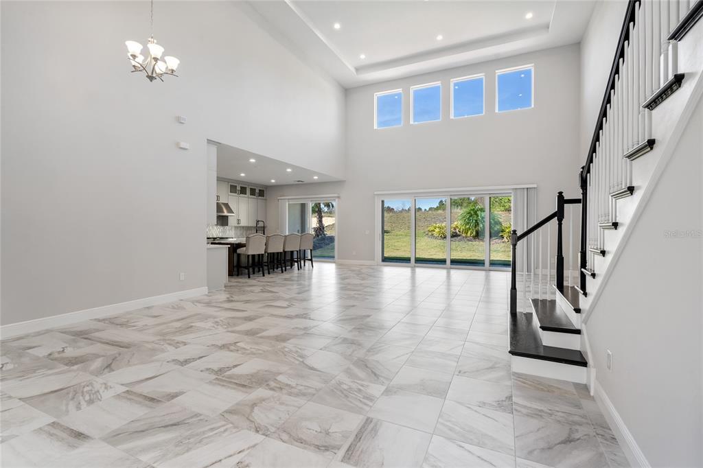 A spacious living area features high ceilings, tile flooring, a staircase, and large sliding doors — 16829 BOLSENA DRIVE, MONTVERDE, FL