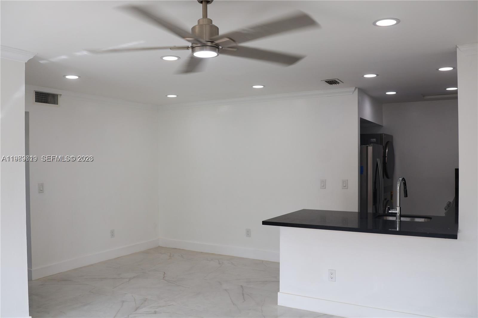 A room with white walls, marble-look tile flooring, a ceiling fan, and a kitchen peninsula — 2550 W 67th Pl # 32, Hialeah FL 33016, HIALEAH, FL