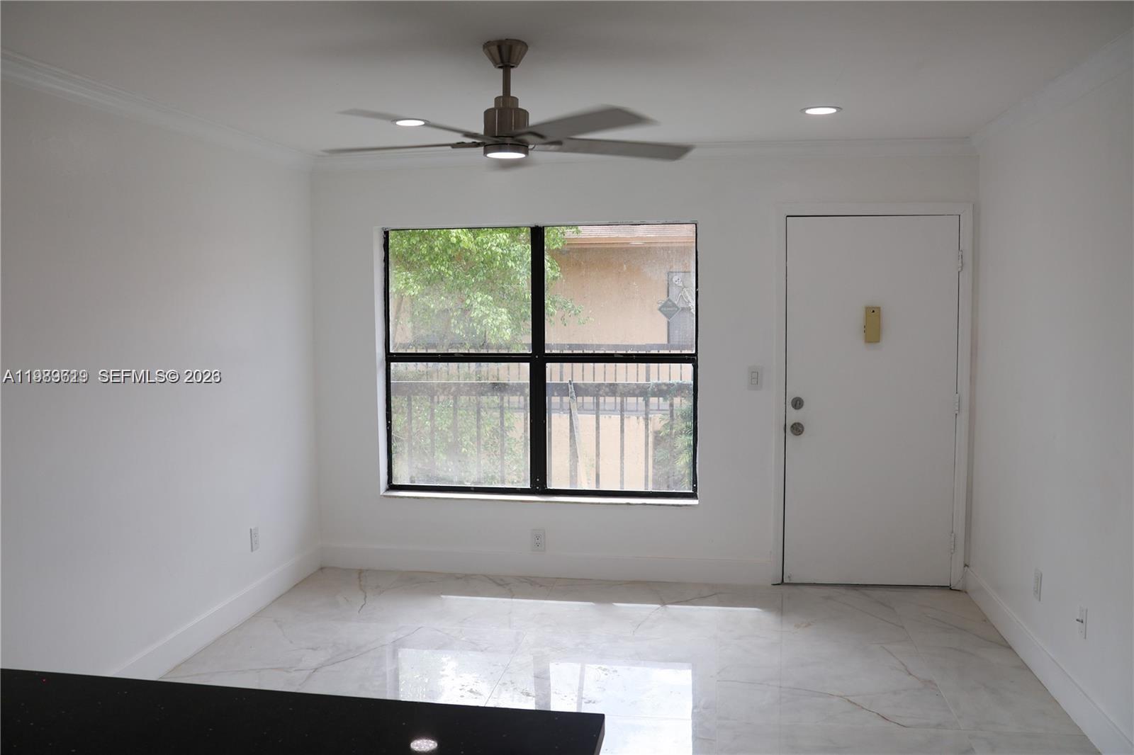 A bright room features white walls, marble-look tile flooring, a ceiling fan, and a window — 2550 W 67th Pl # 32, Hialeah FL 33016, HIALEAH, FL