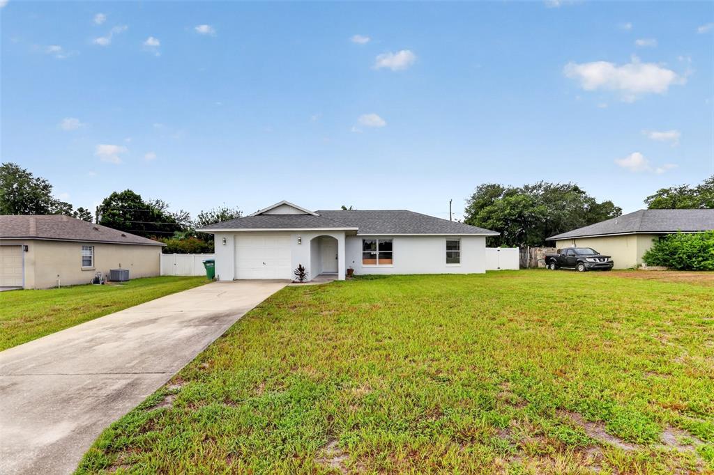 A single-story house with a white exterior, a concrete driveway, and a gray shingled roof — 2941 BEDFORD STREET, DELTONA, FL