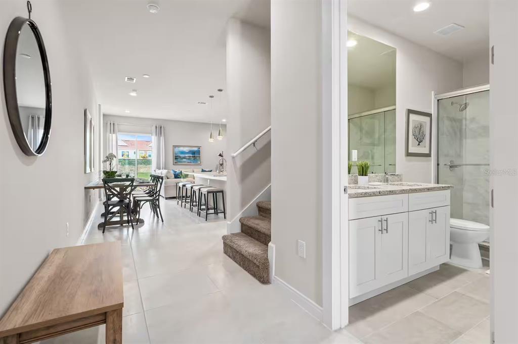 A view from a hallway looking toward a dining area, kitchen, and a bathroom — 7568 SUNFLOWER CIRCLE, KISSIMMEE, FL