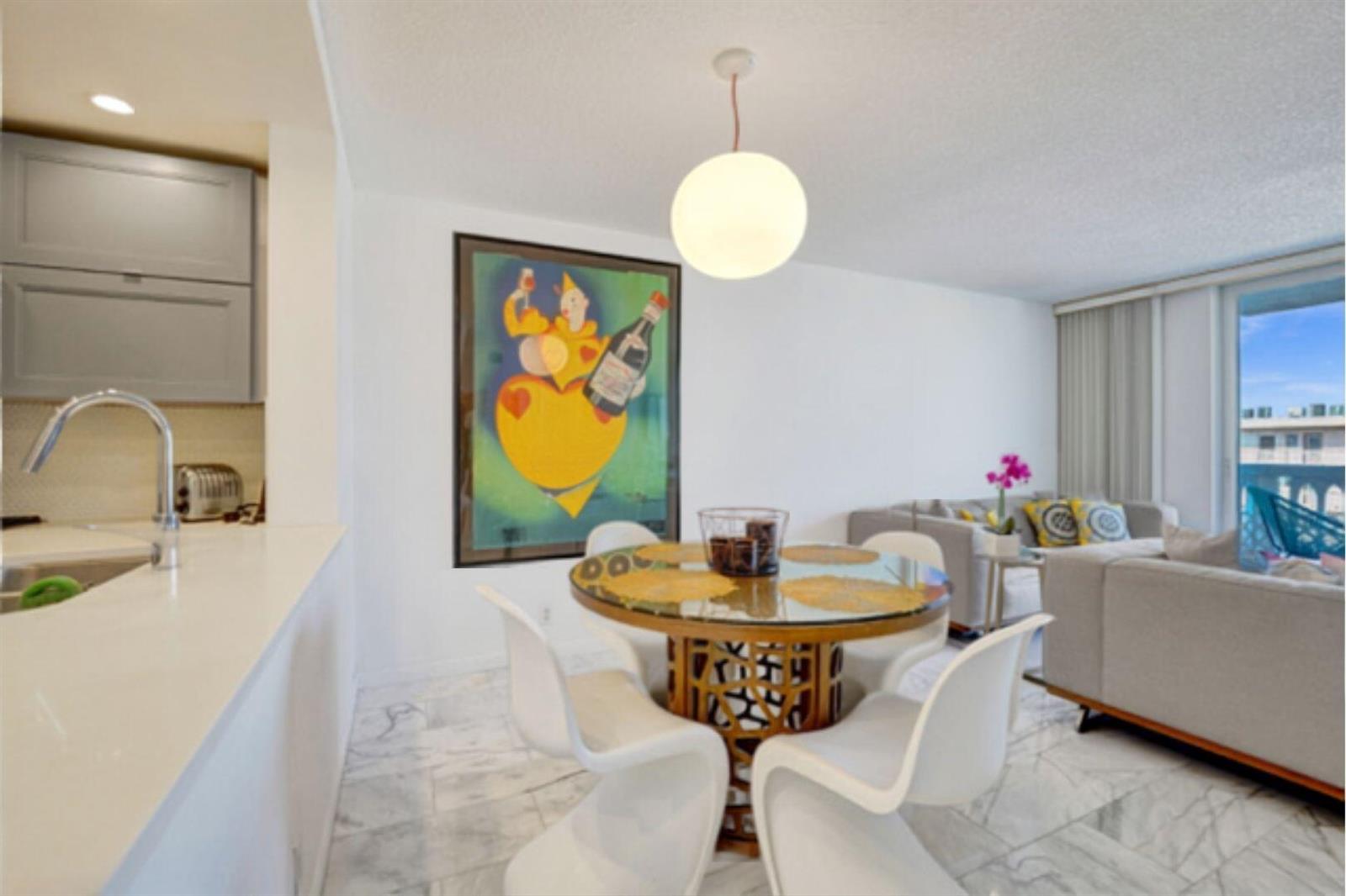 A dining area with a glass-topped table, white chairs, and a large framed poster — 401 NE 14th Avenue # 705, FL 33009, FL