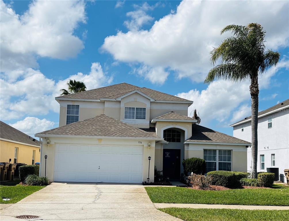 A two-story suburban house with a white garage, beige siding, and a palm tree — 936 LAKE BERKLEY DRIVE, KISSIMMEE, FL