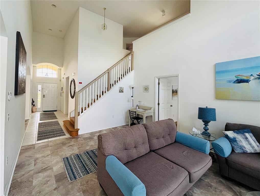 A living room features a staircase, tiled floors, and a view toward the front entryway — 936 LAKE BERKLEY DRIVE, KISSIMMEE, FL
