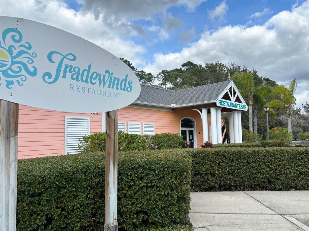 A peach-colored restaurant building with a white sign and a hedge in the foreground — 115 ROGUES RETREAT UNIT 115, DAVENPORT, FL