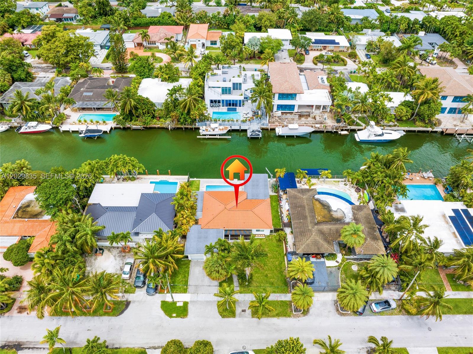 An aerial view shows a waterfront house with a red tile roof and swimming pool — 1161 NE 86th St, Miami FL 33138, MIAMI, FL