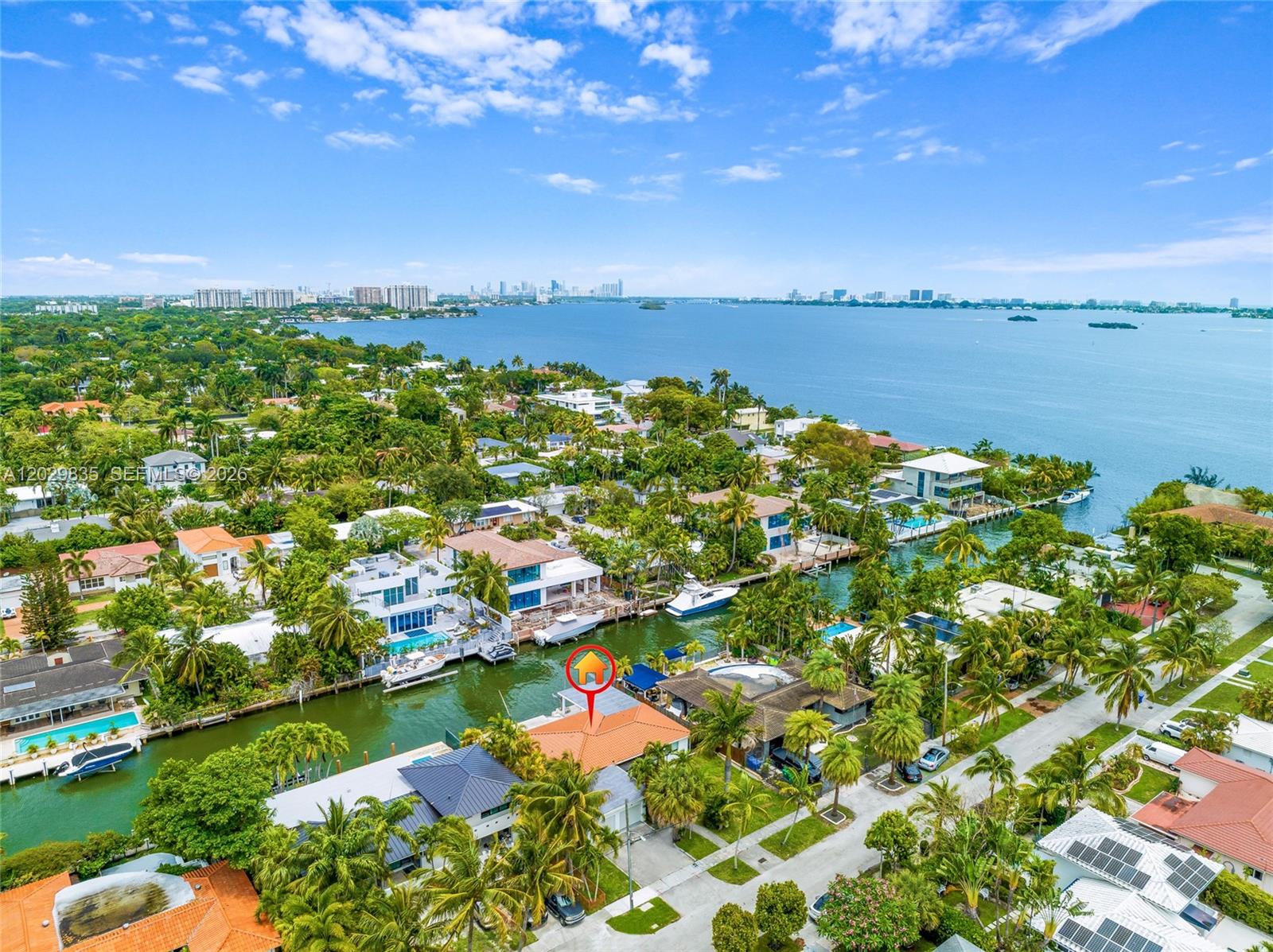 An aerial view shows a waterfront house with a red-tiled roof along a canal — 1161 NE 86th St, Miami FL 33138, MIAMI, FL