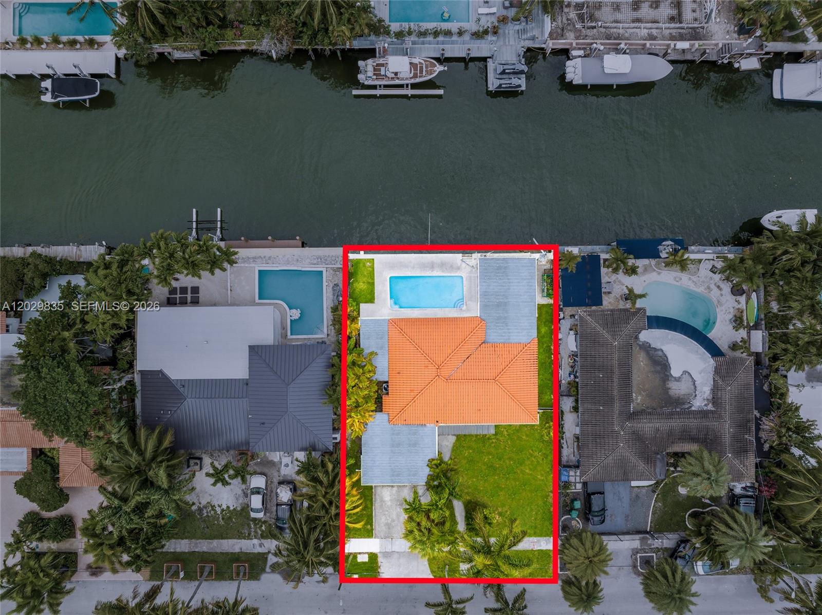 An aerial view shows a house with an orange tile roof, pool, and waterfront dock — 1161 NE 86th St, Miami FL 33138, MIAMI, FL