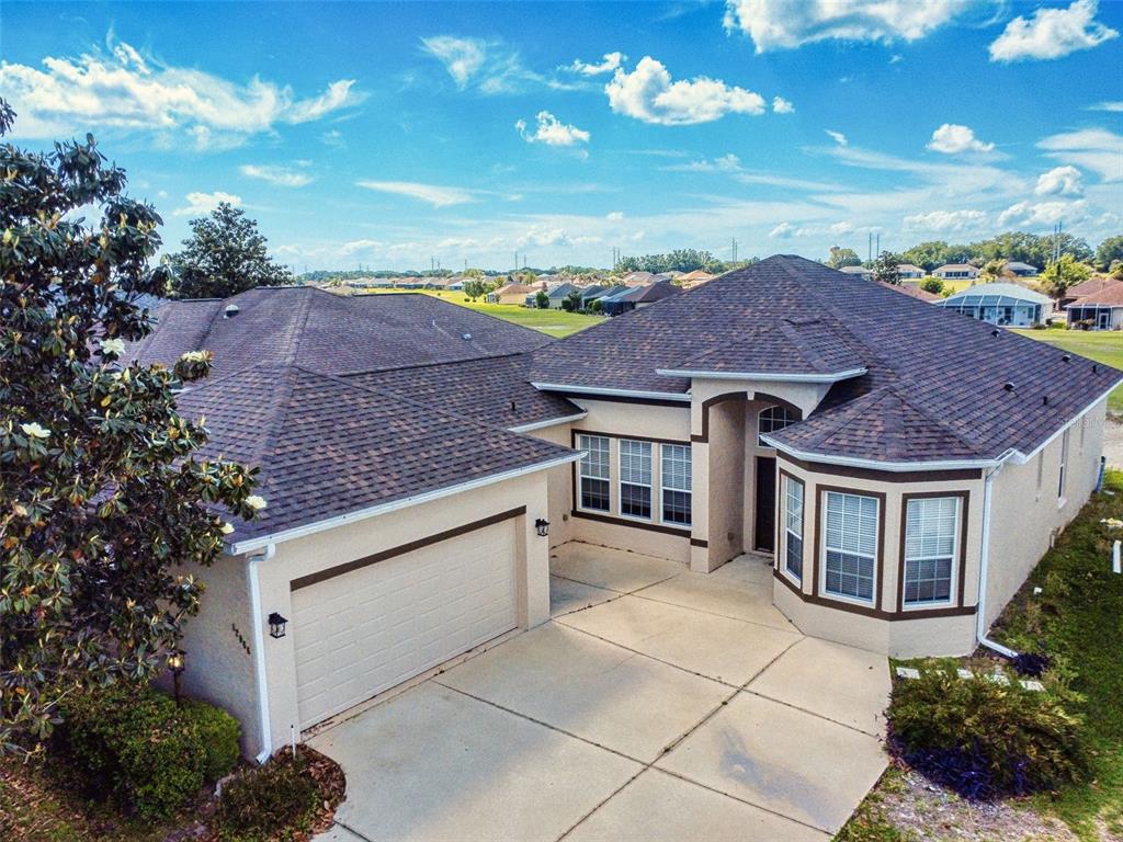 An aerial view of a single-story suburban house with a concrete driveway and shingled roof — 12066 SE 176 LOOP, SUMMERFIELD, FL