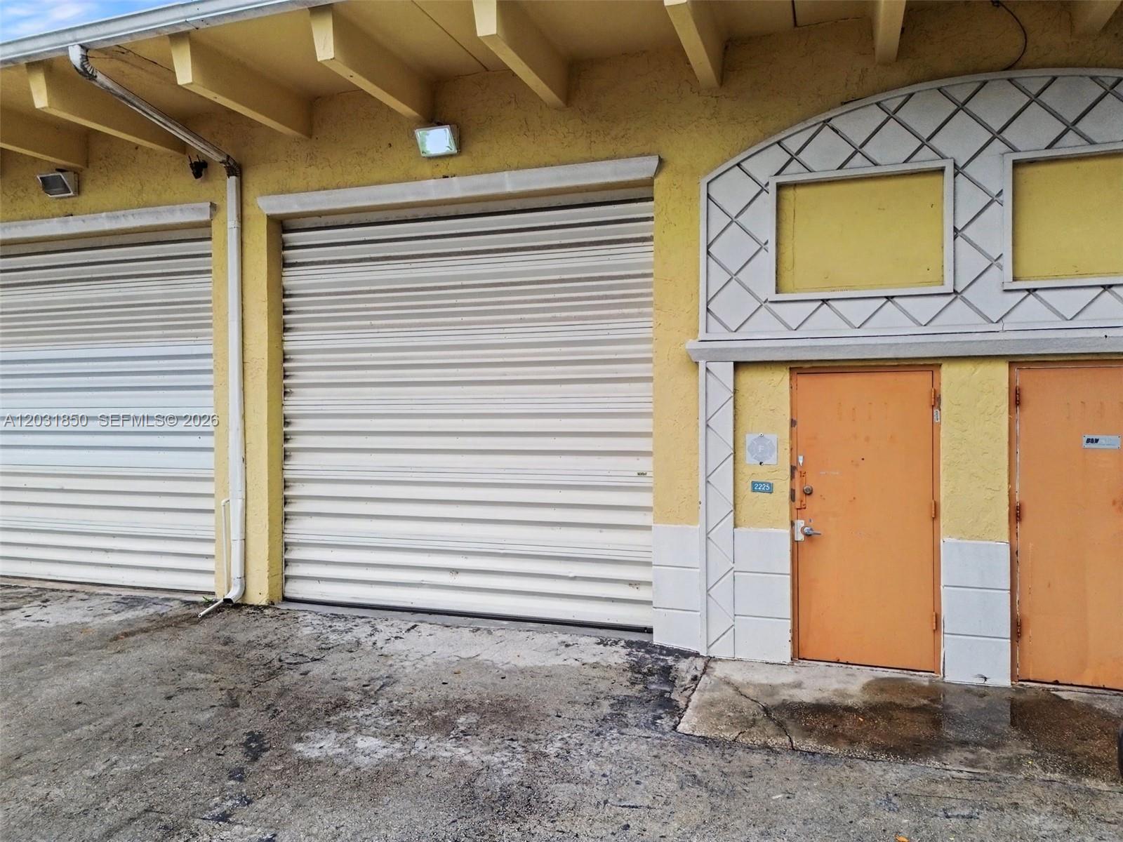 The exterior of a commercial building features two roll-up doors and two orange metal doors — 2225 SW 57th Ave # 2, West Park FL 33023, WEST PARK, FL